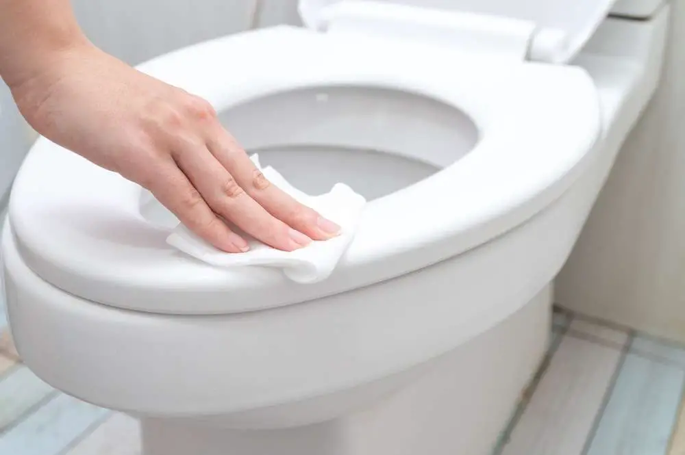 hand cleaning toilet seat with a wipe