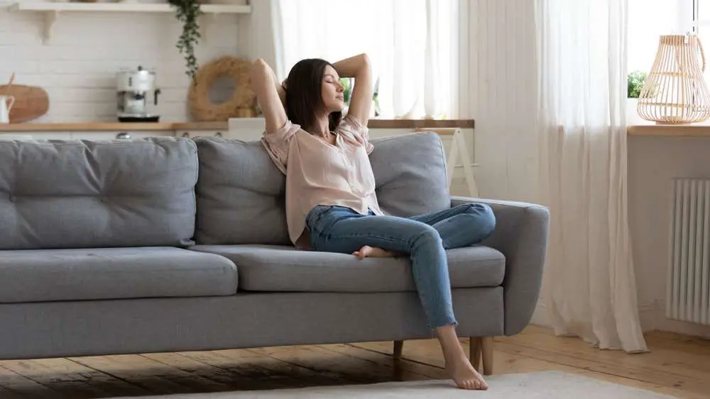calm young woman rest on comfort couch with eyes closed breath fresh air in cozy clean modern living room
